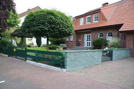 Vorgarten in Soest mit Natursteinmauer, Gartentor und Industriezaun